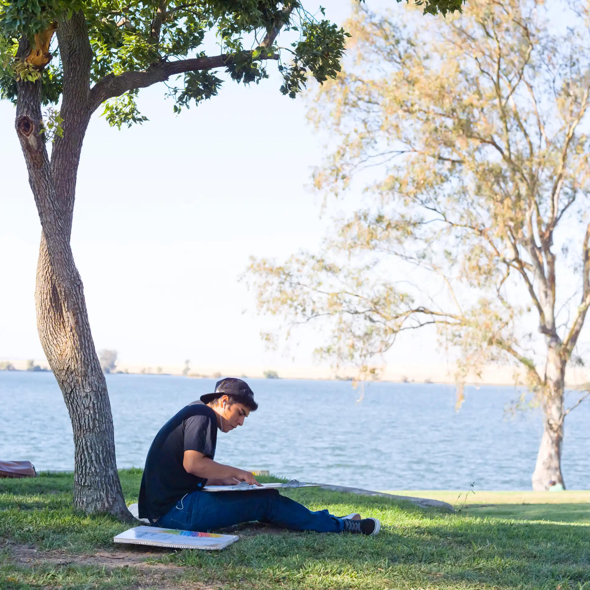 UC Merced student studying under a tree at Lake Yosemite.